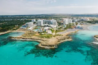 Aerial view of a resort area with clear turquoise waters and sandy beaches in Paphos, Cyprus.