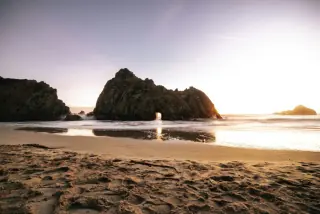 Sunset view of a beach with a natural rock arch formation in Paphos, Cyprus.