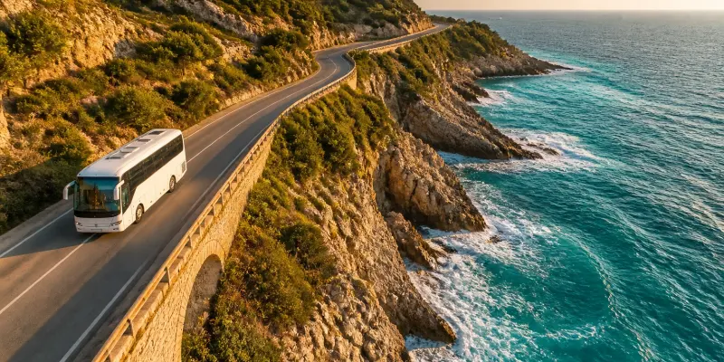 Tour coach on a Mediterranean coastal road at golden hour, aerial view